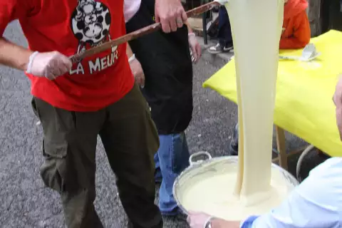 Aligot filé à la louche depuis un grand chaudron, texture élastique caractéristique de la tome fraîche fondue