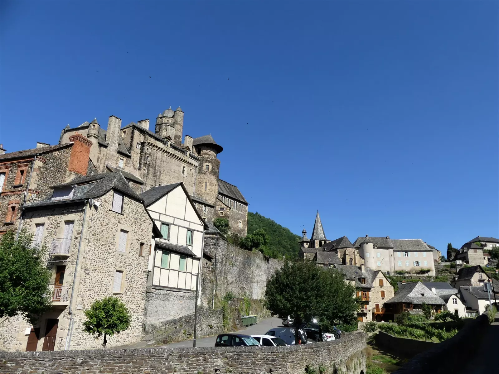Le château d'Estaing dominant le village sous un grand ciel bleu, en Aveyron