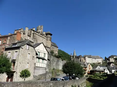 Le château d'Estaing dominant le village sous un grand ciel bleu, en Aveyron