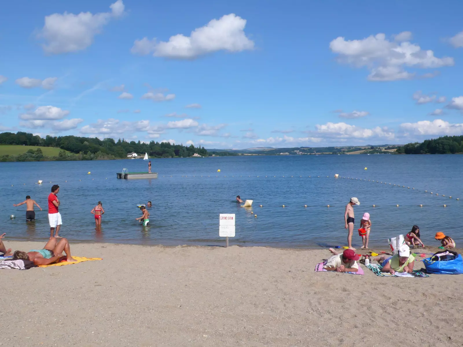 Famille se baignant sur une plage aménagée du lac de Pareloup, sur le plateau du Lévézou en Aveyron