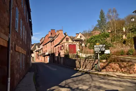 Rue du village de Villecomtal en Aveyron, maisons en grès rouge et pans de bois